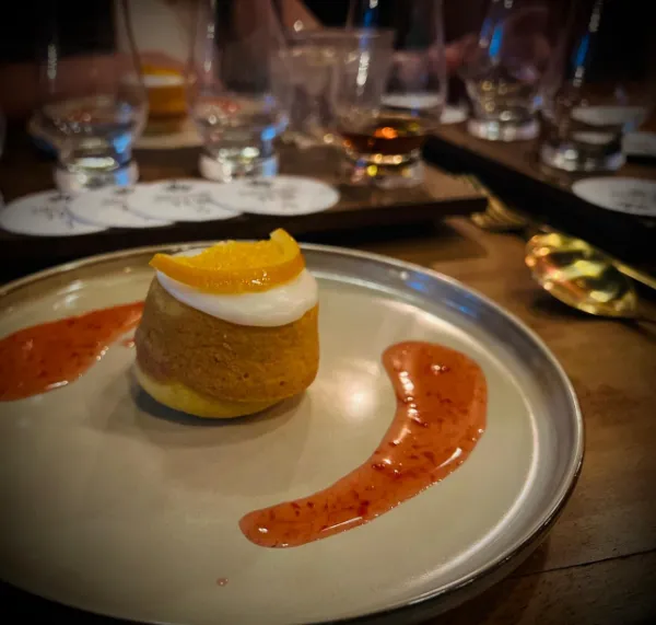 Postre de naranja con glaseado y salsa de frutos rojos; atrás, las copas de la cata sobre posavasos de Bistroteq