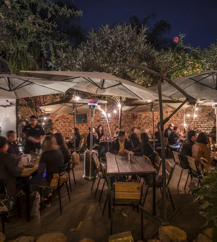 La terraza de Bistro 77 de noche, con sombrillas y luces cálidas